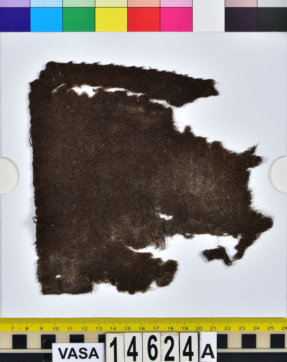 Textil.
Tre fragment uppdelade på fyndnummer 14624a-b.
Fnr 14624a består av två fragment av ull vävda i tuskaft samt valkade på ena sidan. Det ena fragmentet är litet och har troligen lossnat från det stora fragmentet. Det stora fragmentet har två bevarade originalkanter.
Fnr 14624b består av ett fragment av ull vävt i tuskaft samt valkat på ena sidan. Fragmentet har två bevarade originalkanter.