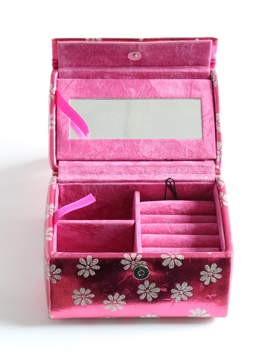 Tilhørt jente (f. 2001) i Sør-Odal. 
Et rosa bærbart smykkeskrin med hvite glitter blomster. Inne i skrinet er det speil og tre ulike rom til å ha ulike smykker i.
