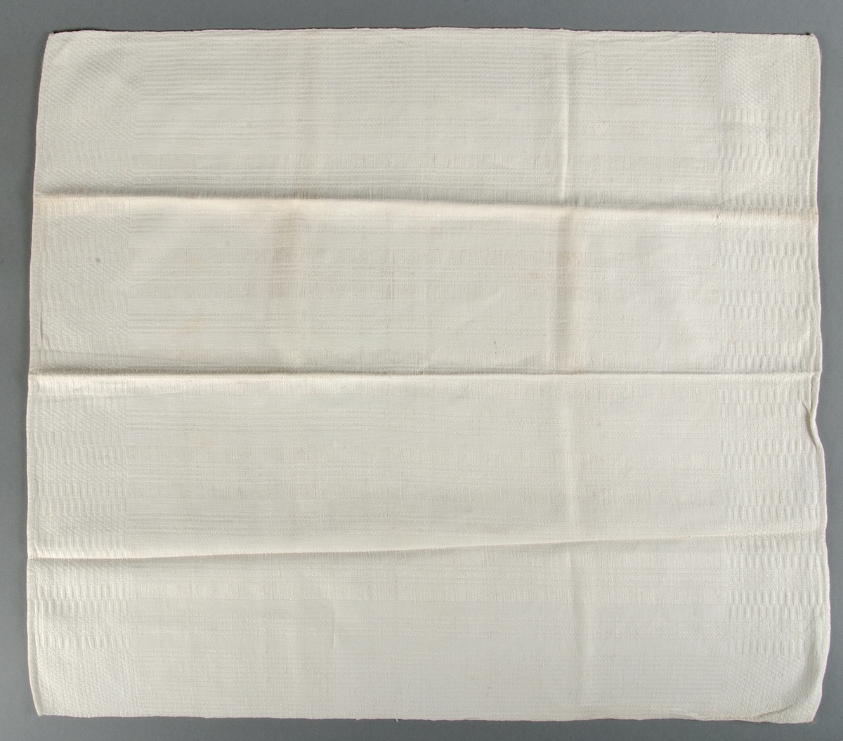 Handduk av vitt halvlinne hemvävd i rutig dräll. Varp av bomull, inslag av lingarn.