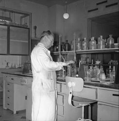Mann i kvit frakk ved reagensrøyr, laboratoriet DNZ, Zinken,