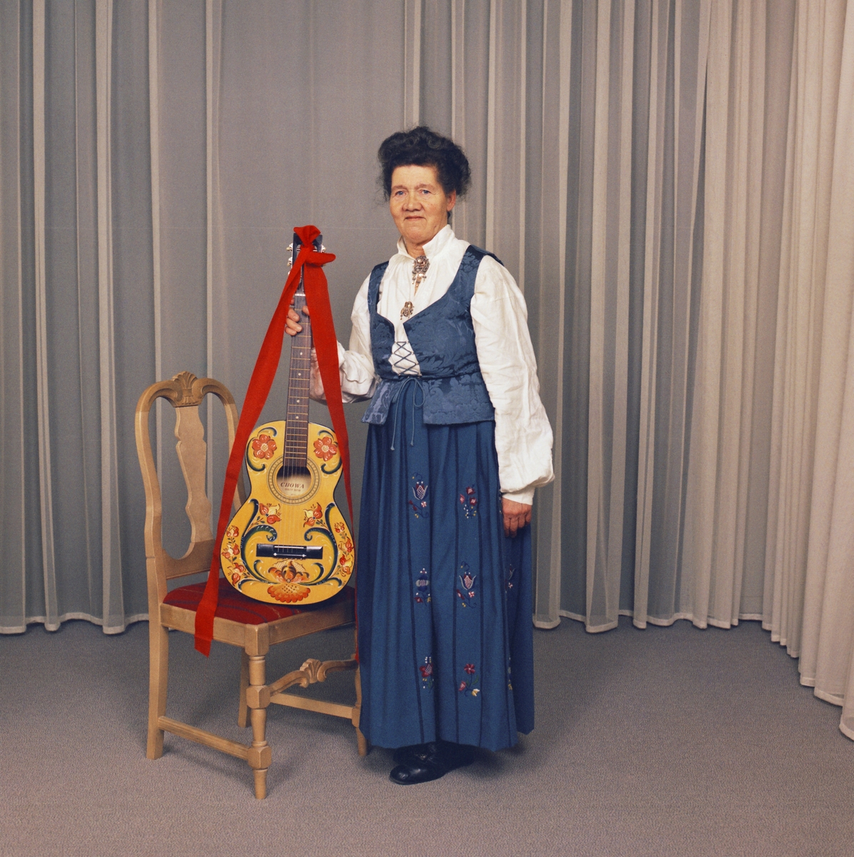 Bunadskledd kvinne med rosemaltgitar fotografert i studio på Strømmen