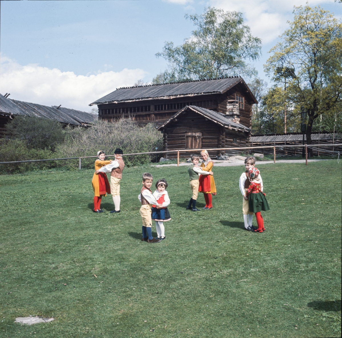 Dansande barn på Orsakullens gräsmatta iklädda folkdräkt.