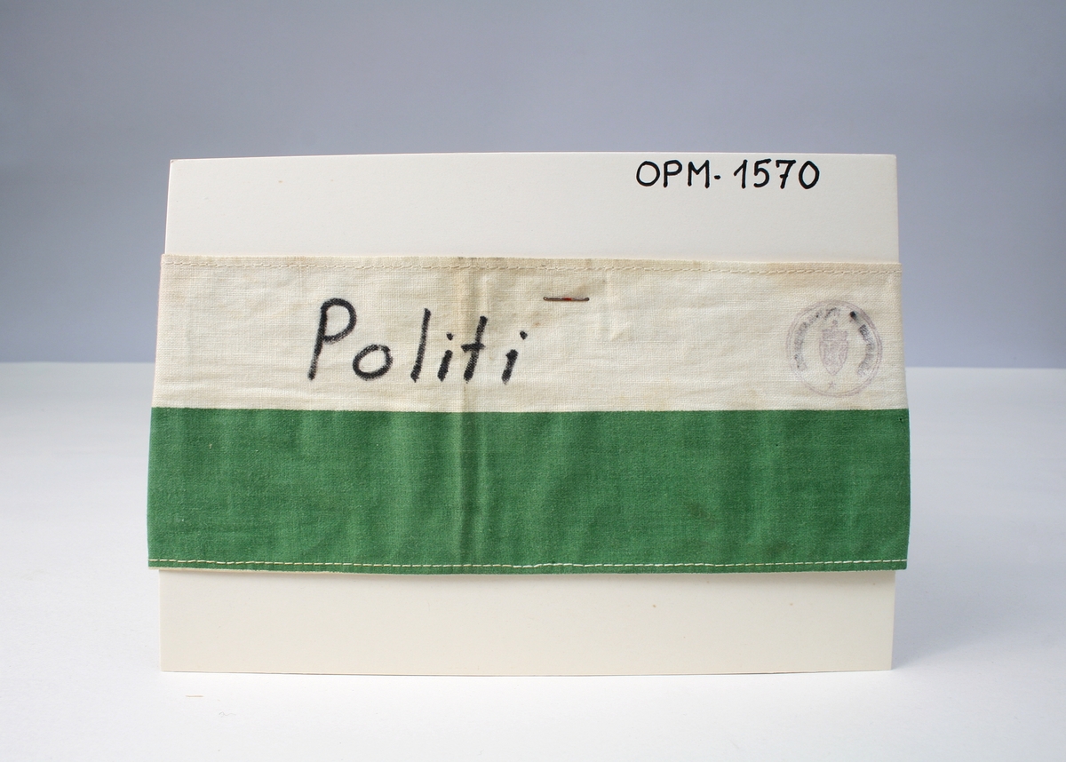 Type 1940, armbindet er i grønt og hvitt, i det hvite feltet teksten "Politi" med svarte, håndskrevne bokstaver.