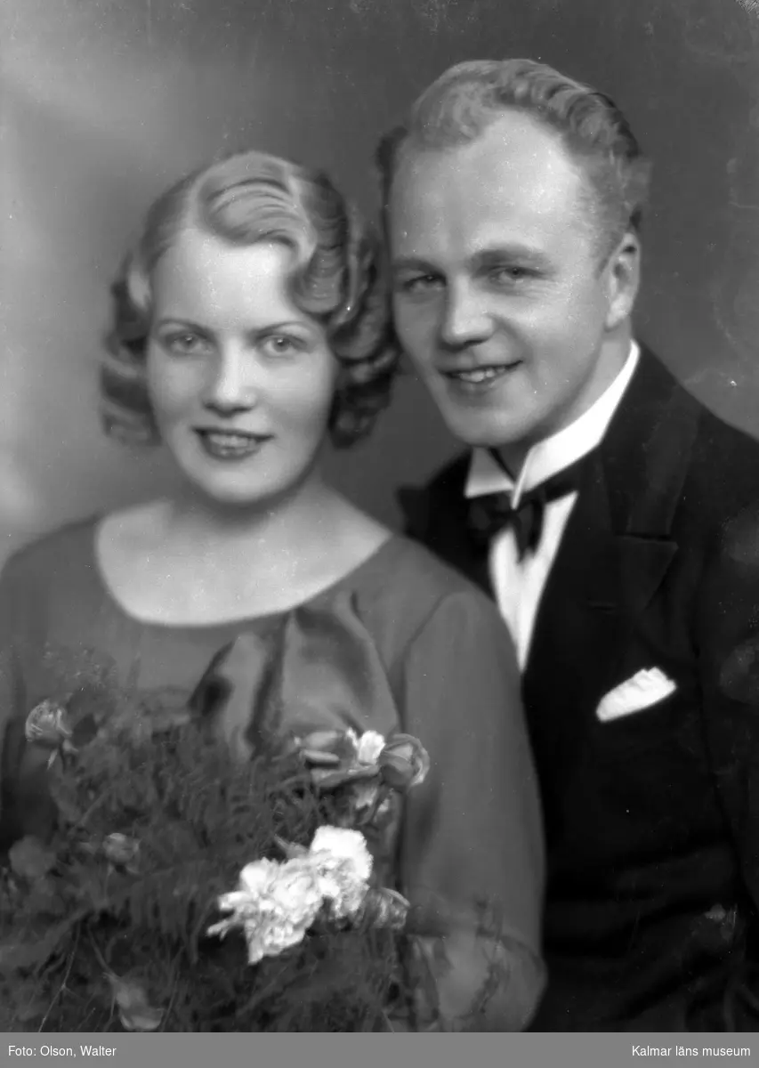 Ateljébild på eventuellt ett brudpar. Kvinnan har en blombukett. Enligt Walter Olsons journal är bilden beställd av Erling Claësson.