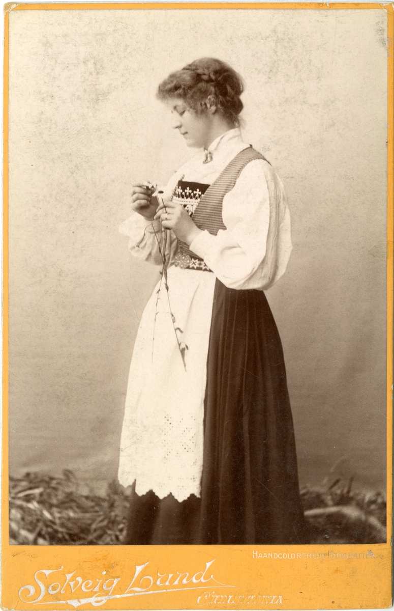 Studiofotografi av kvinne med Hardangerdrakt og to prestekrager.