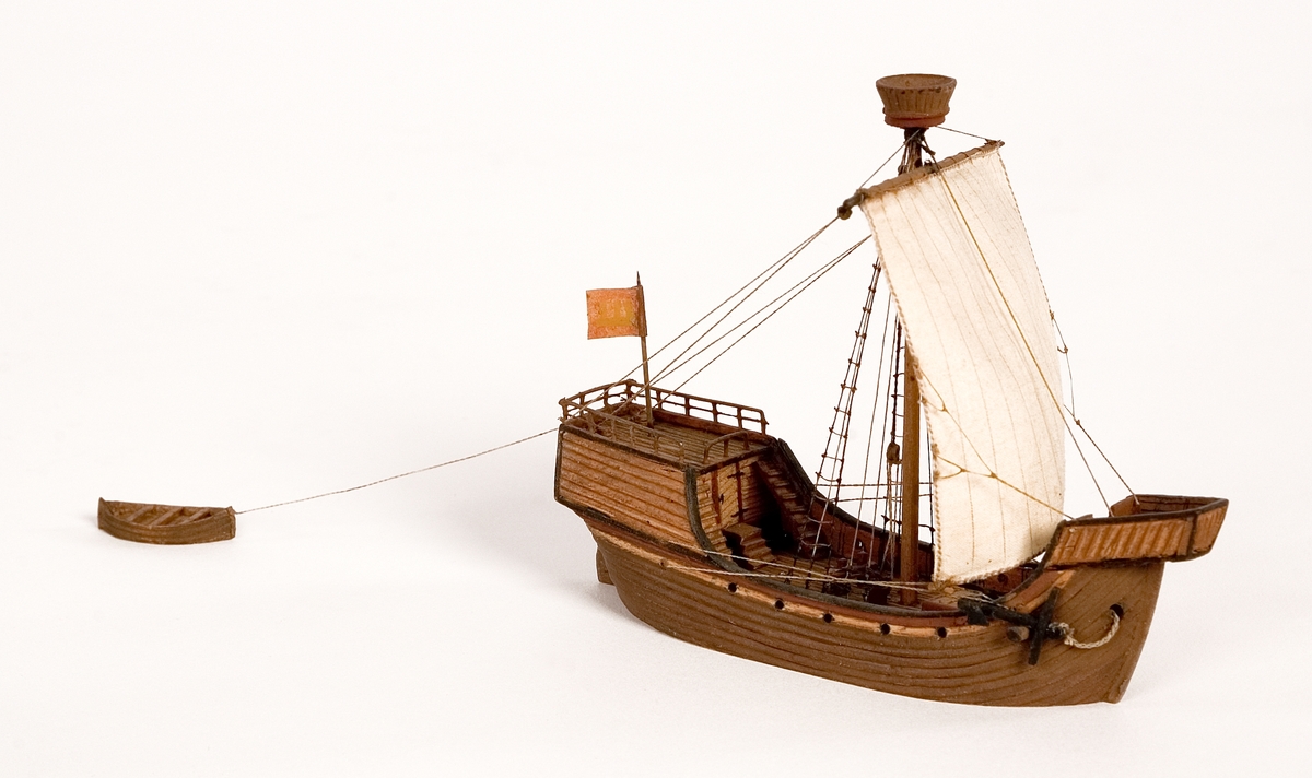 Fartygsmodell, vattenlinjemodell, hel i block av trä, kogg (1400-talet). Brunt skrov med höga kastell i för och akter Riggad med 1 mast med ett råsegel, rund stridsmärs. På akterkastellet stång med röd flagga med heraldiskt vapen. Utrustad med skeppsbåt.Föremålets form: Vattenlinjemodell