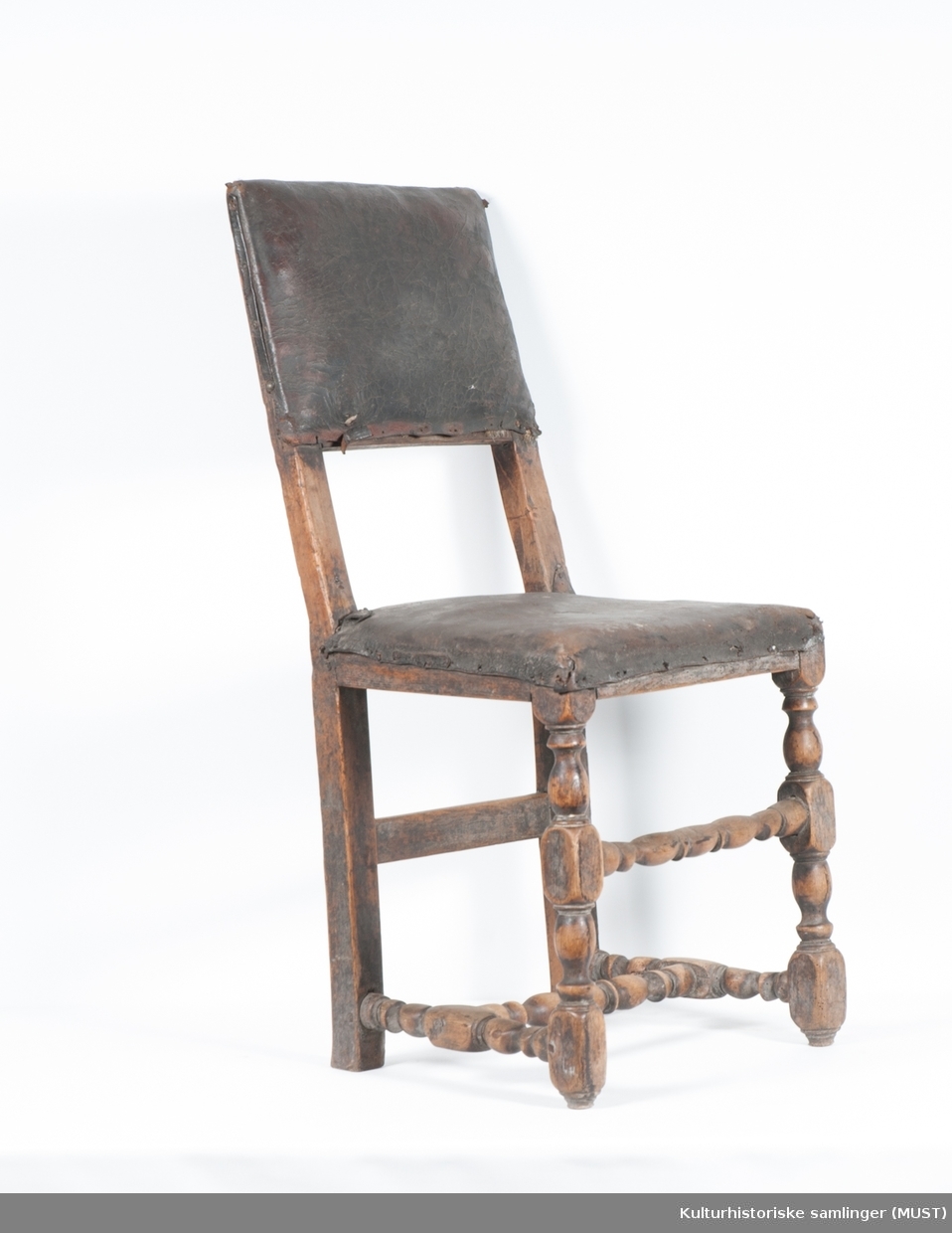 Fast sete. Setet og rygg er trukket med svart skinn, antagelig originalt. Stolen har dreide forbein og sprosser.