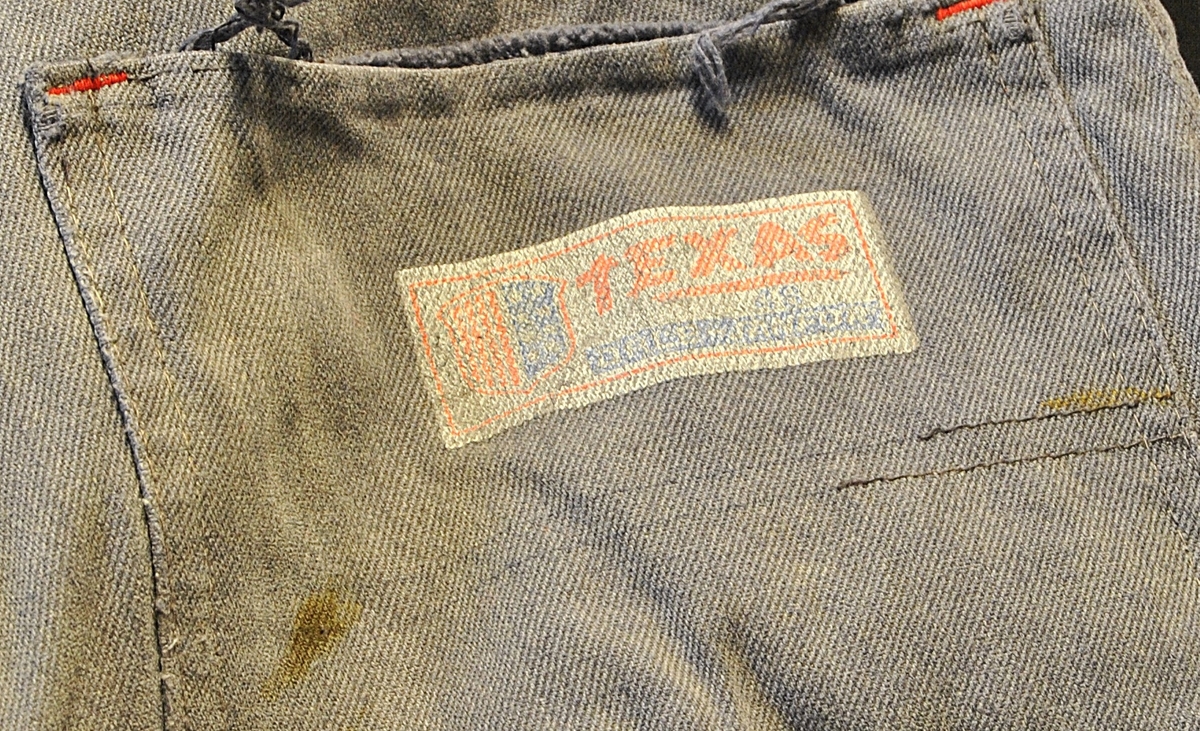 Arbeidsbukse av dongristoff. Bærer preg av bruk. Lappet flere ganger.