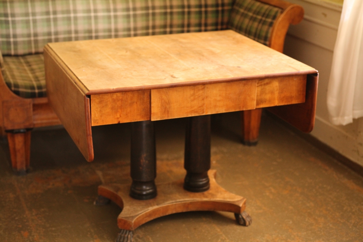 Klaffebordet er av lys polert bjørk, foten består av 2 sorte søiler og en bjørk underplate med 4 løveføtter