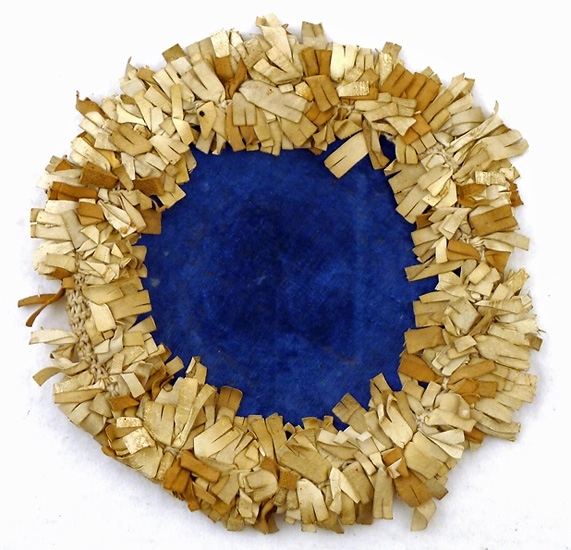 Lamjpmatta, rund, blå sammet i mitten, gråvita skinnremsor trädda på en virkad kant runtom, baksidan av ljust brunt bomullstyg, pappskiva inuti. Lika som 69.559.
 
Auktion 1933-05-13