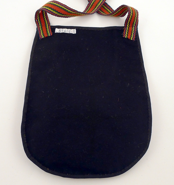 Enl liggare:
"Kjolväska, svart kläde med applikationer i gult, rött och blått. Handvävt randigt axelband"