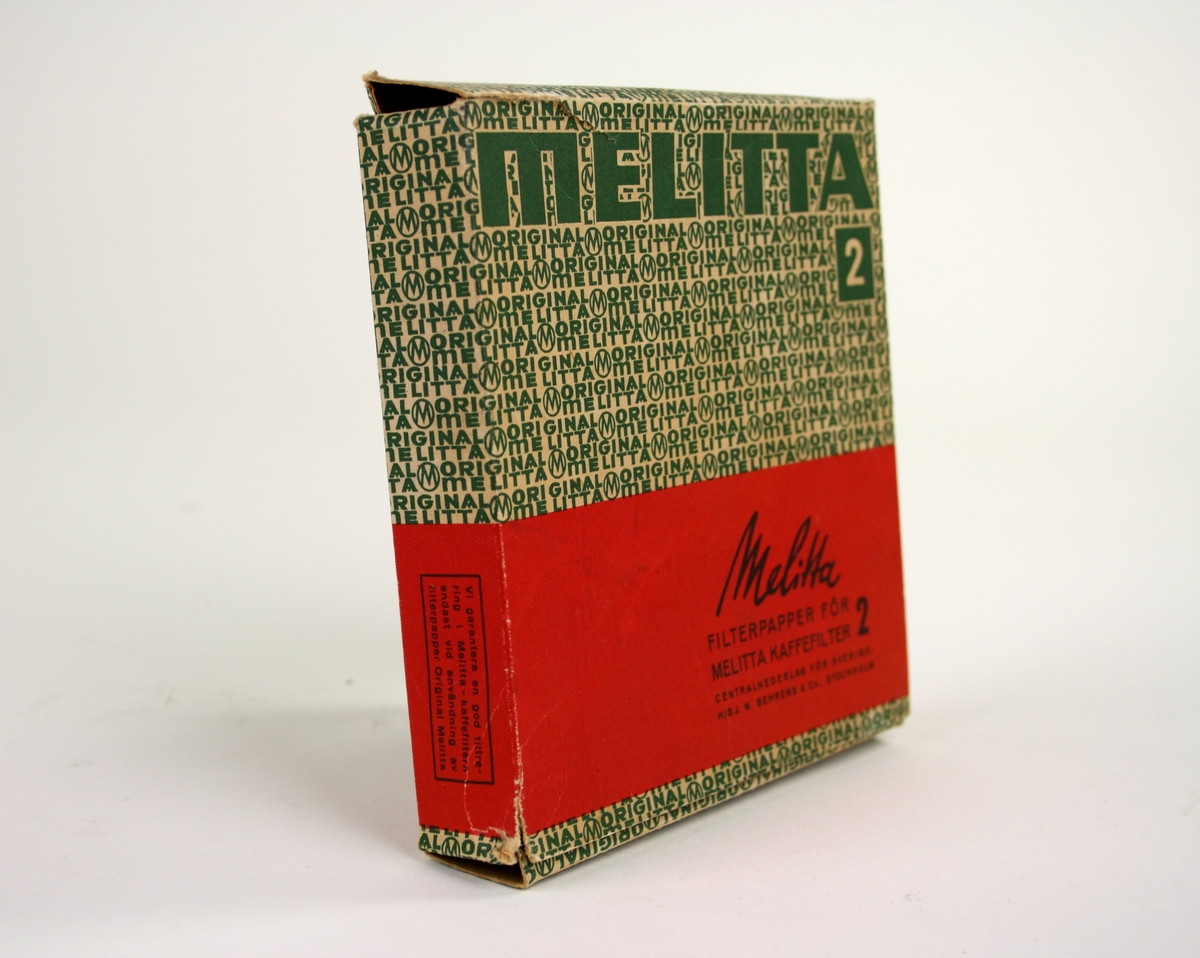 Förpackning för kaffefilter i kartong i rött och grönt. Text på förpackningen: "Melitta filterpapper för melitta kaffefilter 2". I förpackningen finns runda filter kvar.