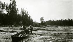 To menn uti elva ved Sandkjellfossen (riksgrensa), drar båte