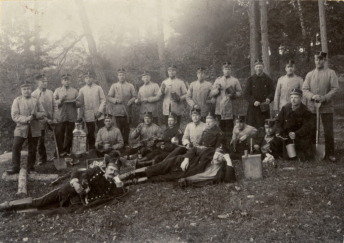 Grupporträtt av manskapssoldater samlade till måltid på Järvafältet omkring 1900-1903.