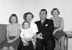 Gruppefoto av en familie sittende i en sofa. Bildene er regi