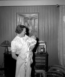 Portrettfoto av mor med sitt nydøpte barn i armene. Det er u