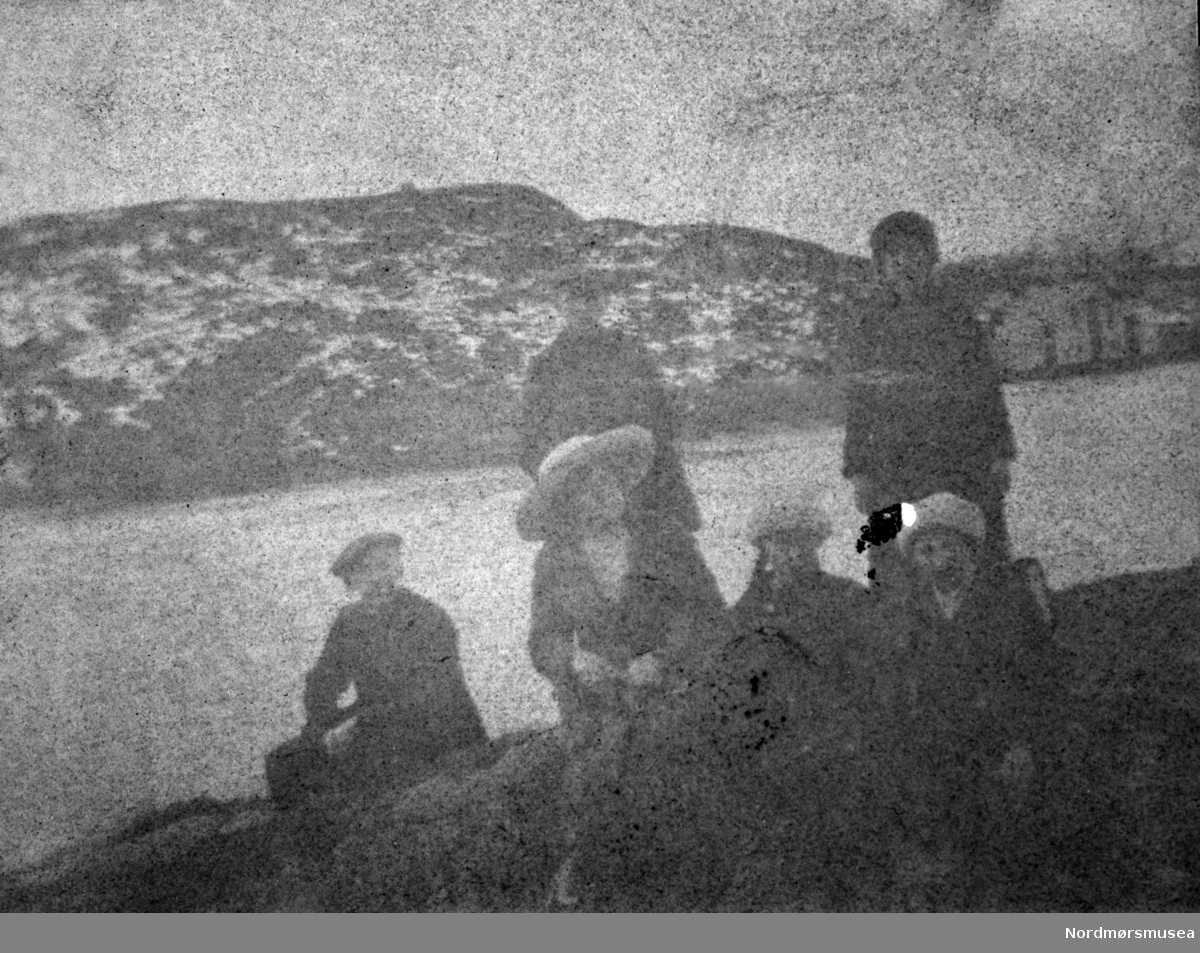 Svært dårlig foto trolig rundt Nordsundet i Kristiansund, hvor vi ser en gruppe mennesker samlet ved sjøkanten. Fra et fotoalbum tilhørende Ellinor Williams-Phakdikun (1905-1963). Fra Nordmøre museums fotosamlinger.