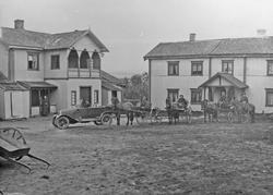 Bolighus, bil, hest, vogn, personer.