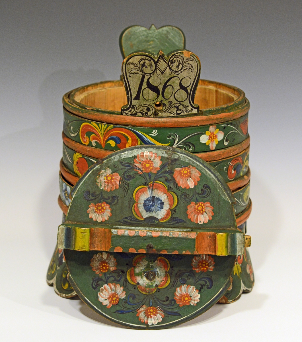 Fra protokollen:
Grøtbøtte, rosemalt av Kittel Østerholt, Lunde. Merket ATD 1868.

Grautspann med lokk. Grautspannet er lagget. Innvendig umalt, utvendig rosemalt. Det er 3 stk brede føtter og tagger i i mellom.