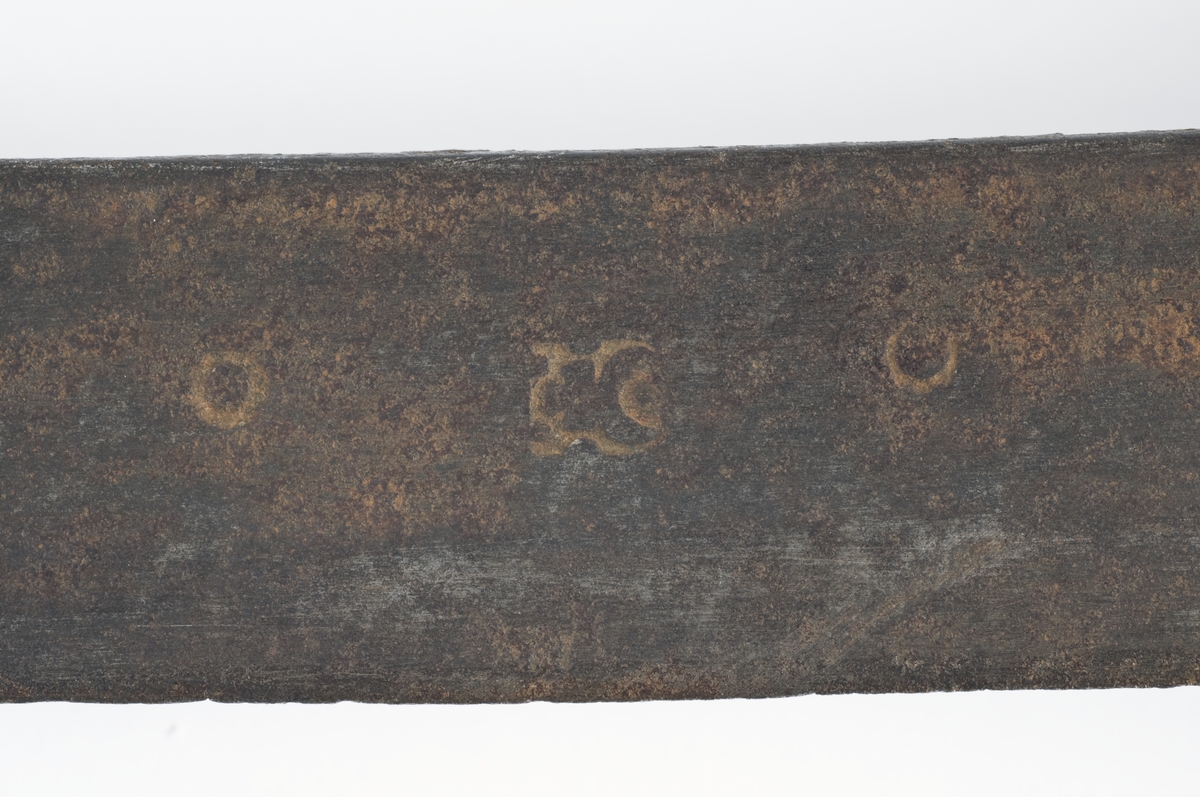 Soppformet  knapp. Tregrep med trådbevikling.  Runde parerstenger og svakt nedbøyd bakre parestang. Fremre parerstang er brukket. Kurvfeste med runde bøyler med utsmidde  midtpartier. Nyreformet parerplate med tombøyle og klingebrekker på innsiden. 
2 sidebøyler på innsiden.
Enegget, kileformet krum klinge med  bred blodrand. Gjeddenebb og ryggslipning mot spissen.  
Klingens innside merket med 3 smedstempler.