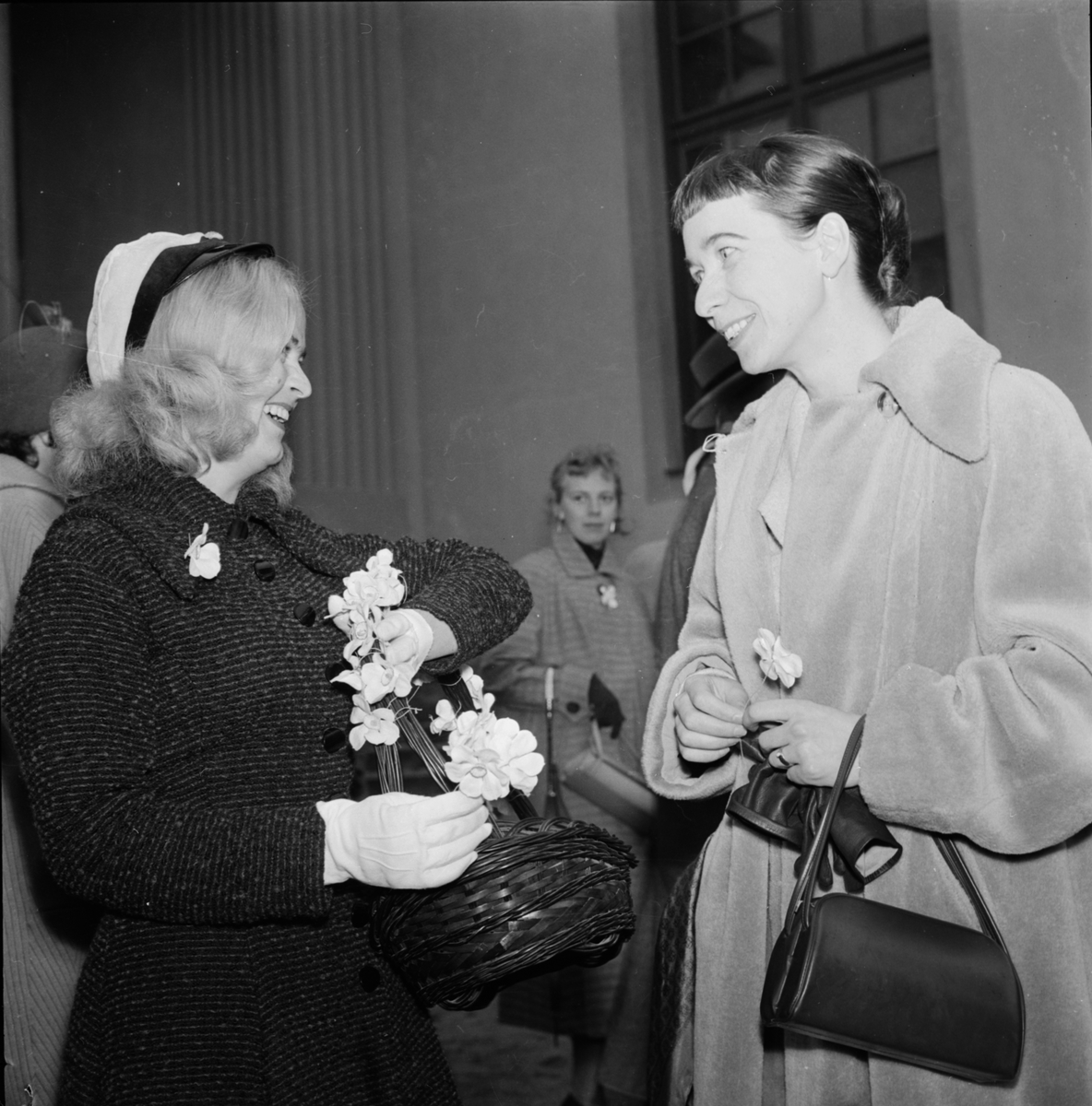 Sara Lidman och kvinnlig student med vårfestblommor på Uppsala Studentkårs Vårfest i Botaniska trädgården, Uppsala 1956