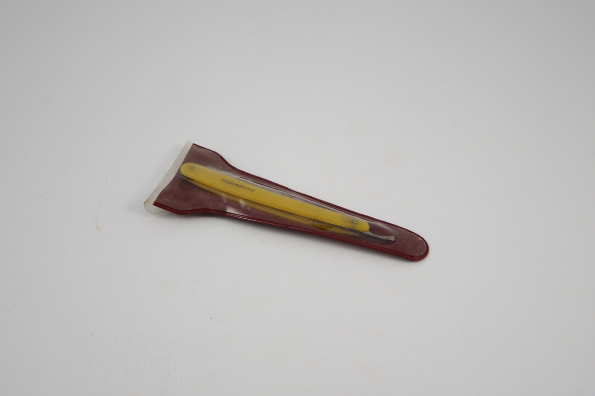 a) Rektangulær kniv, innhukk og smalere flate mot festet. Håndtak: to deler festet m/to skruer, ovale, noe buet form. Kniven kan vris inn mellom disse delene. 
b) Futeral, transparent på den ene side , buet, langstrakt form.