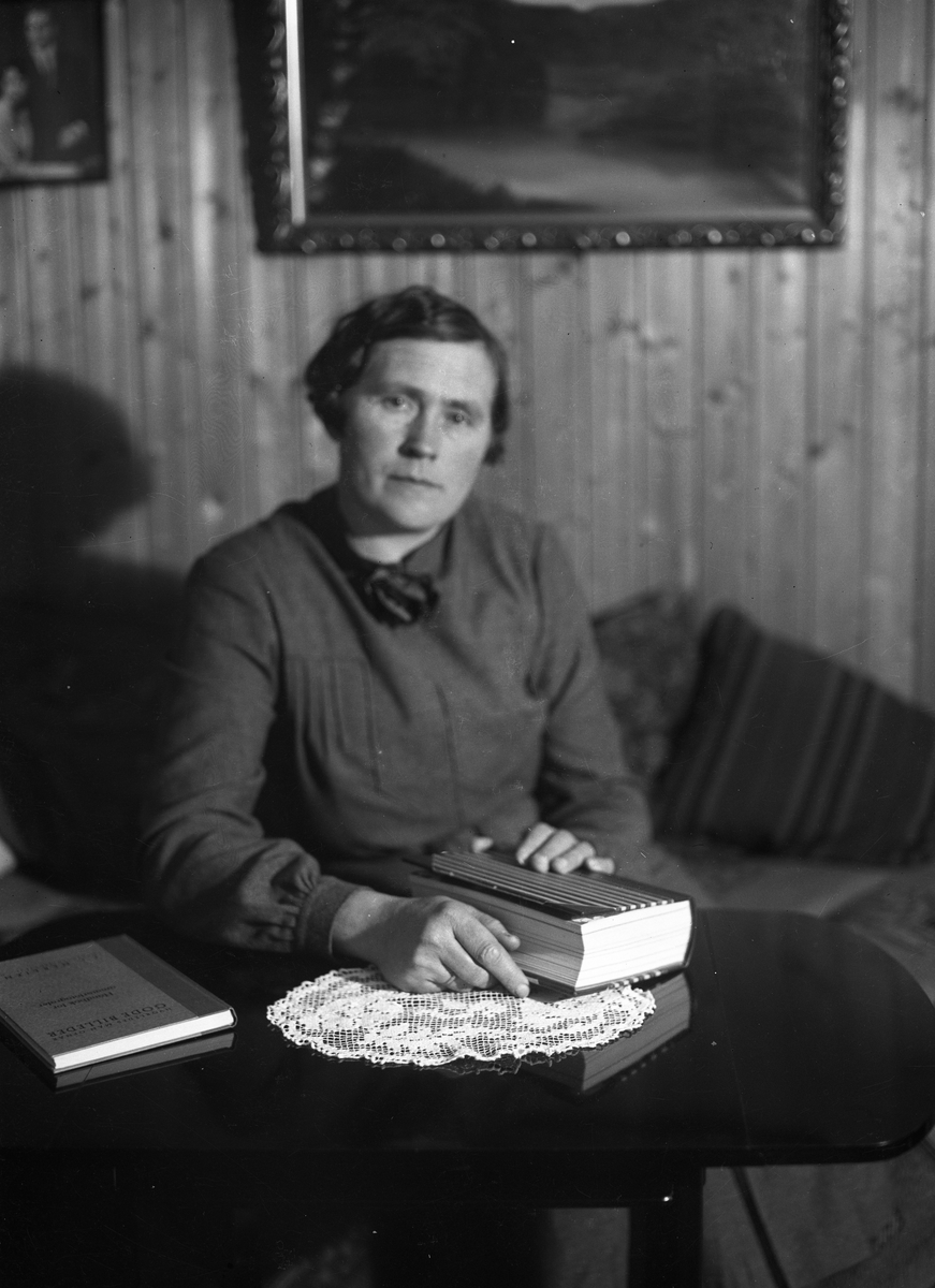 Karine Røisli med en bok ved et bord.