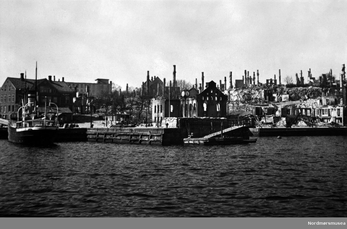 Piren med sundbåtkai, Rutebåt, Til venstre Loennechengården i Kaibakken, Den Høyere Skole, Tollbua, Kristiansund i ruiner 1940. Nordmøre museums fotosamling.