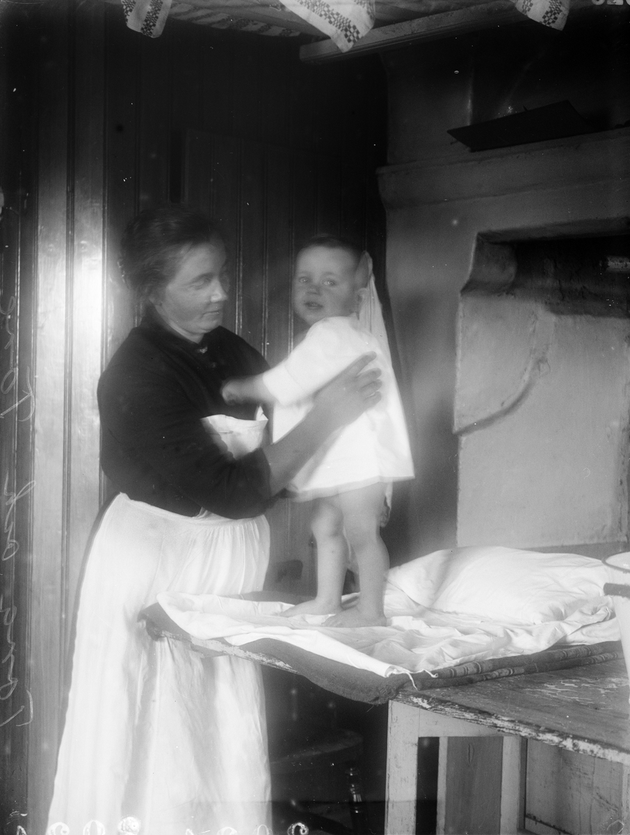 Tora Alinder håller Tore Alinder i köket, Sävasta, Altuna socken, Uppland 1925