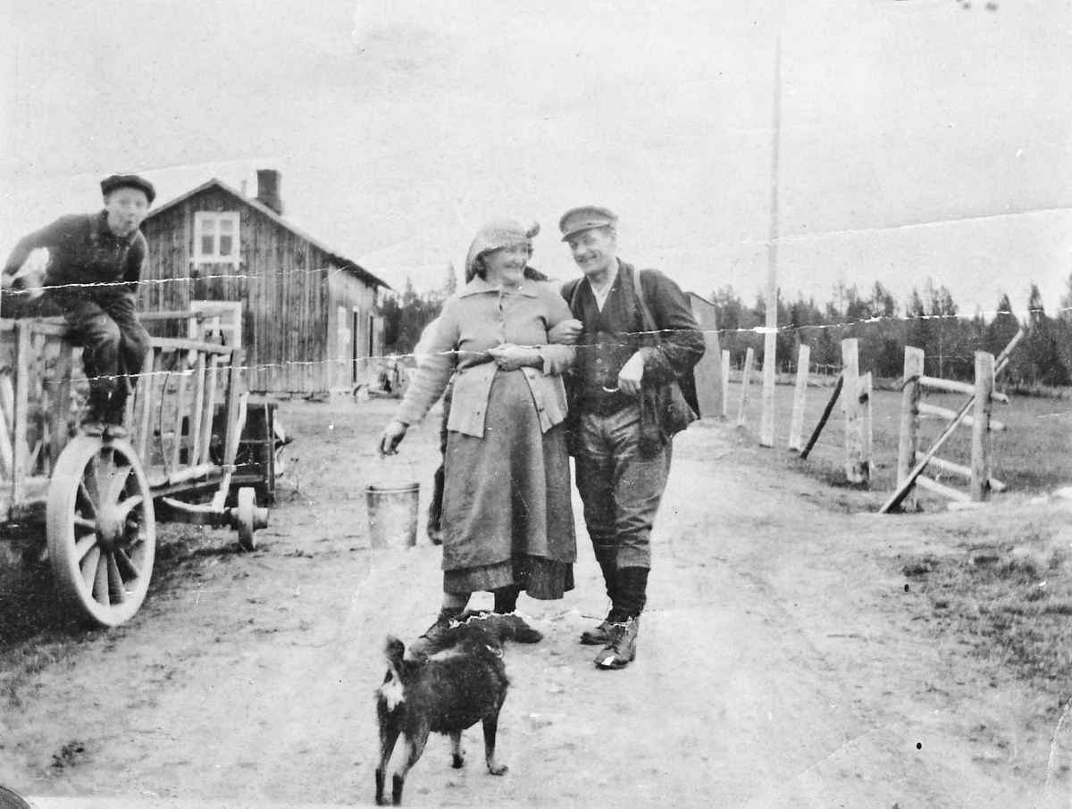 Personer, hund, vogn. 
Bertoline og Olaus Østlund ved Brakka ved veien mellom Øvre og Hanestad. 