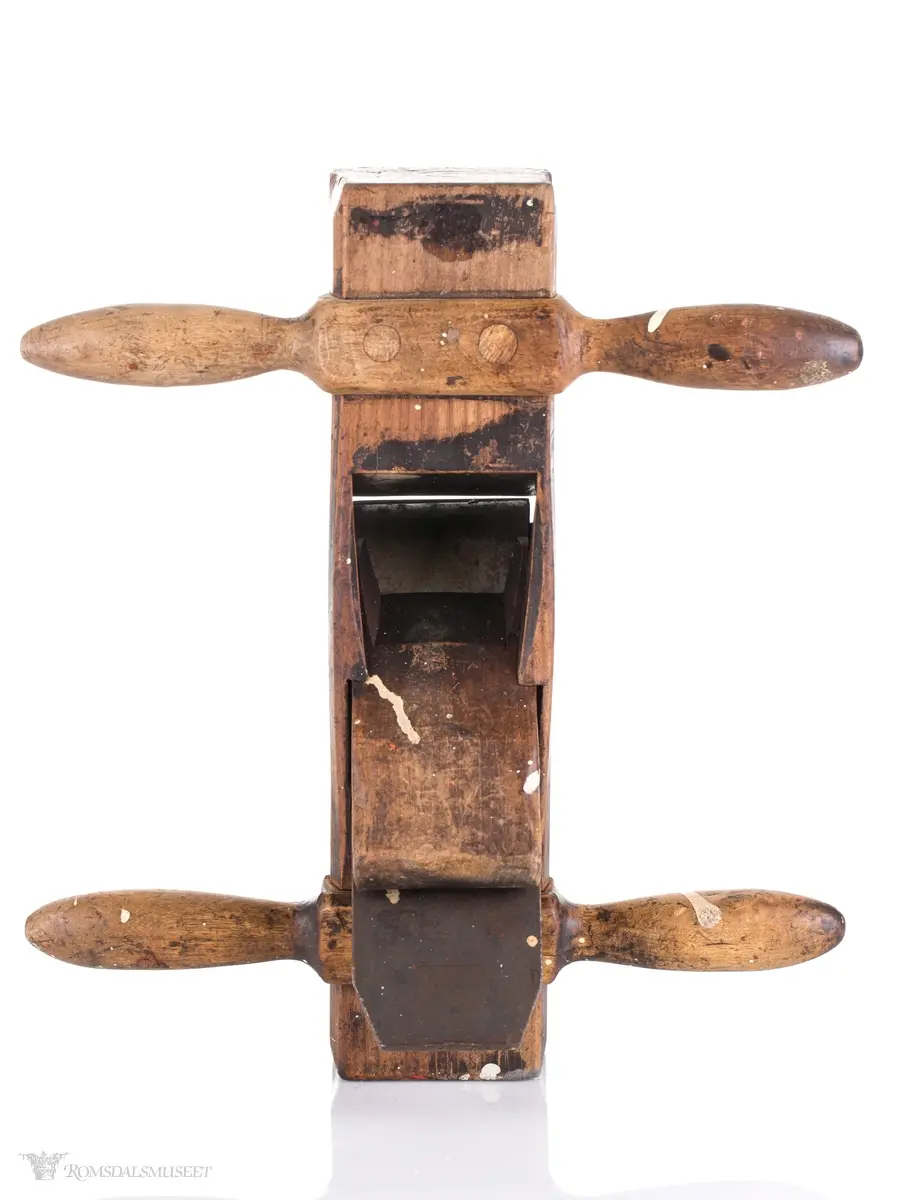 Oksehøvel i tre med rektangulær høvelstokk. Sponhus på toppen med høveljern med klaff og kile. Knekt av tre slått inn i bakkant.