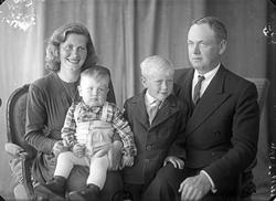 Gruppebilde. Familiegruppe på fire. Mor, far og to unge gutt