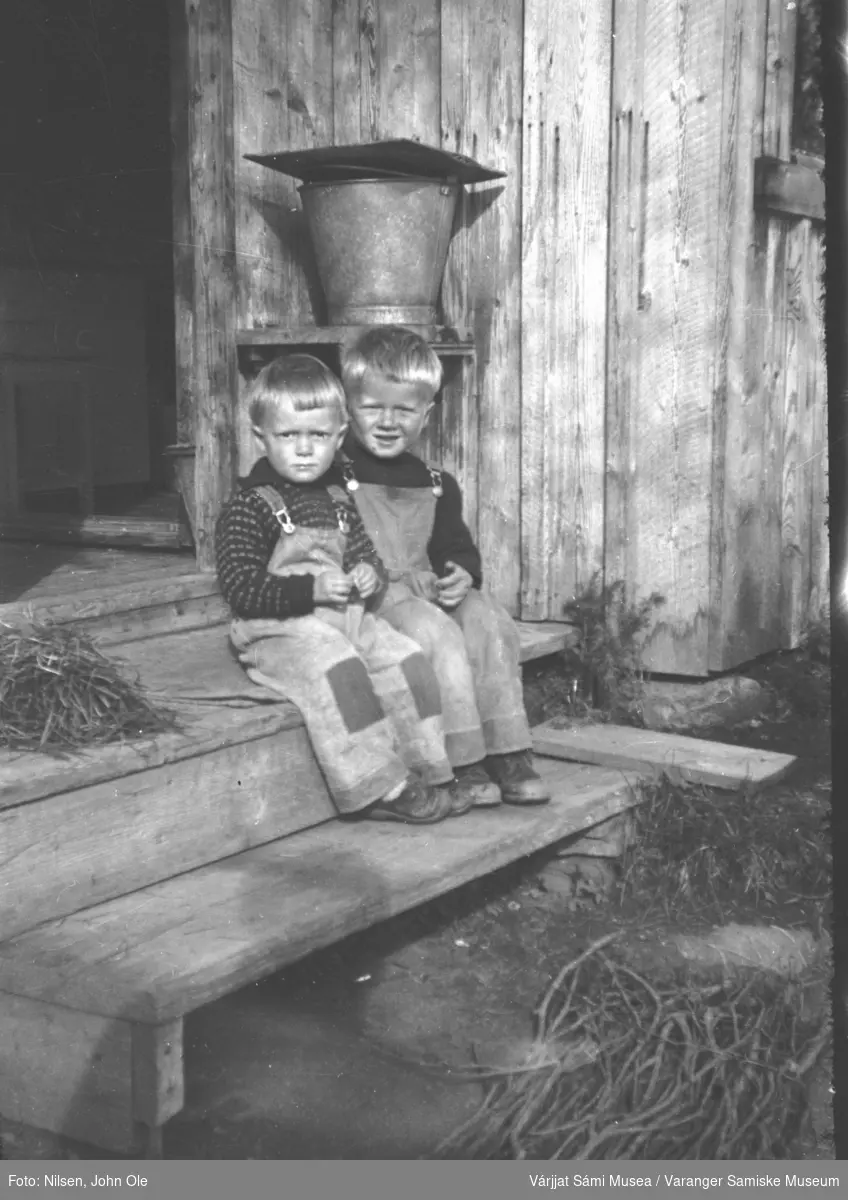 Brødrene John Samuel Nilsen og Kjell Nilsen sitter på trappa i gamlehuset i Fuoitnjárga / Bunes tidlig på 1950 tallet.