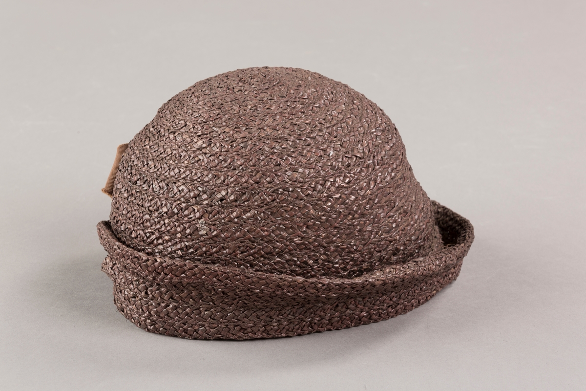 Form: Sirkelformet, avrundet  med brem og lita silkesløyfe med knapp. Bomullsbånd innvendig
Brem oppbrettet i spiralform med bredde økende til avslutning hvor den er festet til pullen med en plastknapp og sløyfe