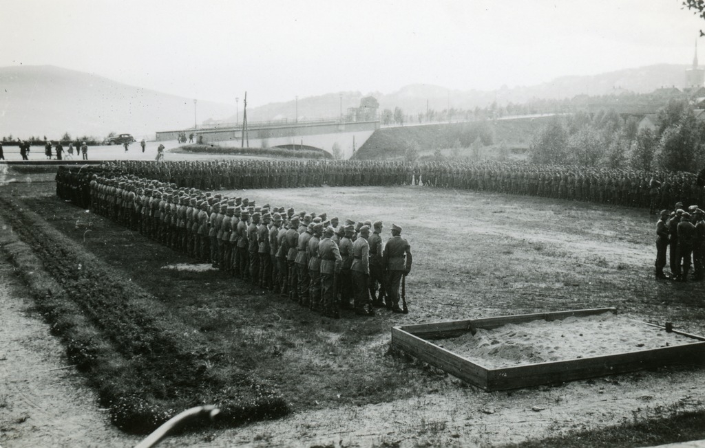Tyske soldater står oppstilt på "Frimerket" i Narvik. Frydenlundsbrua i bakgrunen.