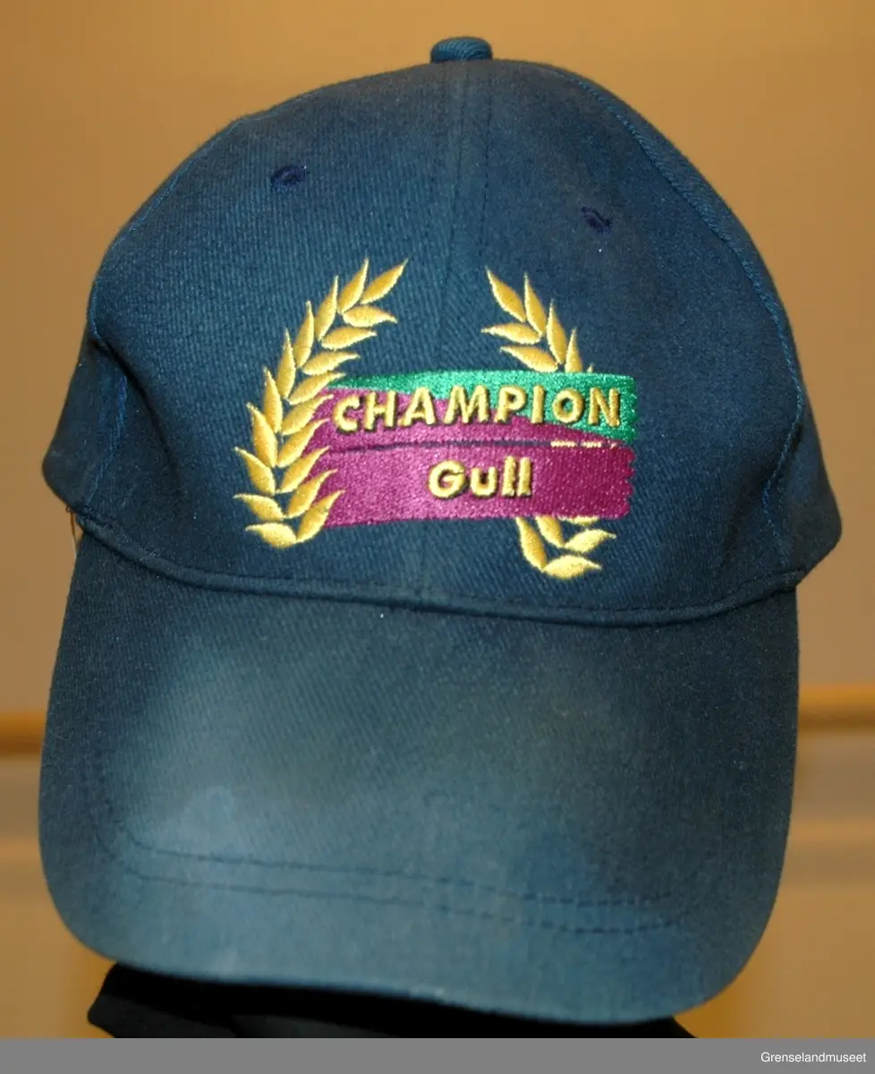 Kjeledress i tre deler, bukse, jakke, skyggelue. jakke st. 54, grønn med gul og lys grønn stripe, bukse grønn, skyggelue blå, st. 59.
Syntetisk stoff