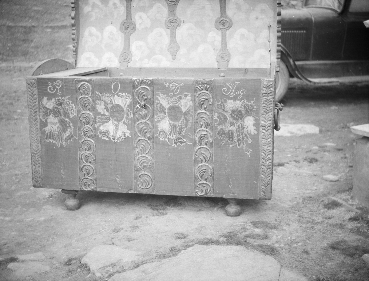 Åpen rosemalt dragkiste står ute på tunet. Dekor både utenpå og inni. Har inskripsjon:"  R O D Hage. Denne kiste erd foreret af fader og moder. Malt dend 22 april 1762".