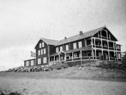 Grotli Høyfjellshotell med biler og buss parkert forran.