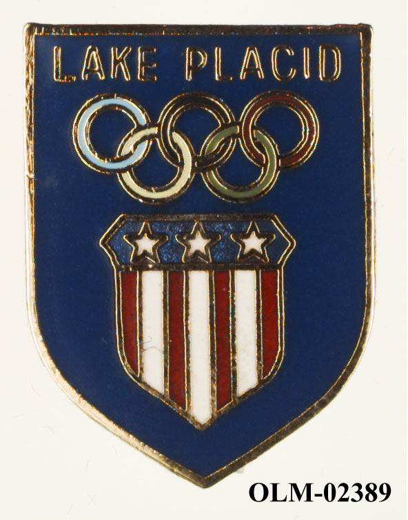 Skjoldformet blått merke med de olympiske ringer og en vimpel med tre hvite stjerner på blå bakgrunn øverst og vertikale striper i hvitt og rødt under.