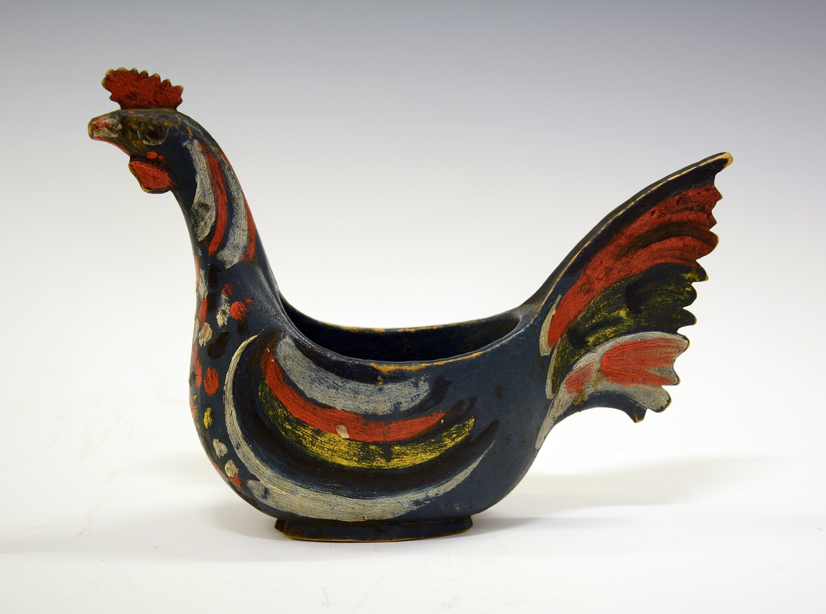 Ølhane. Fra protokollen: Eiskildskop i form av en hane; malt blaa med brogede fjær.