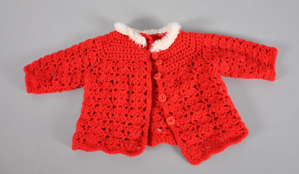 Strikket genser til dukke, rød farge med hvit pelskrage. På framsiden er det 5 røde knapper.