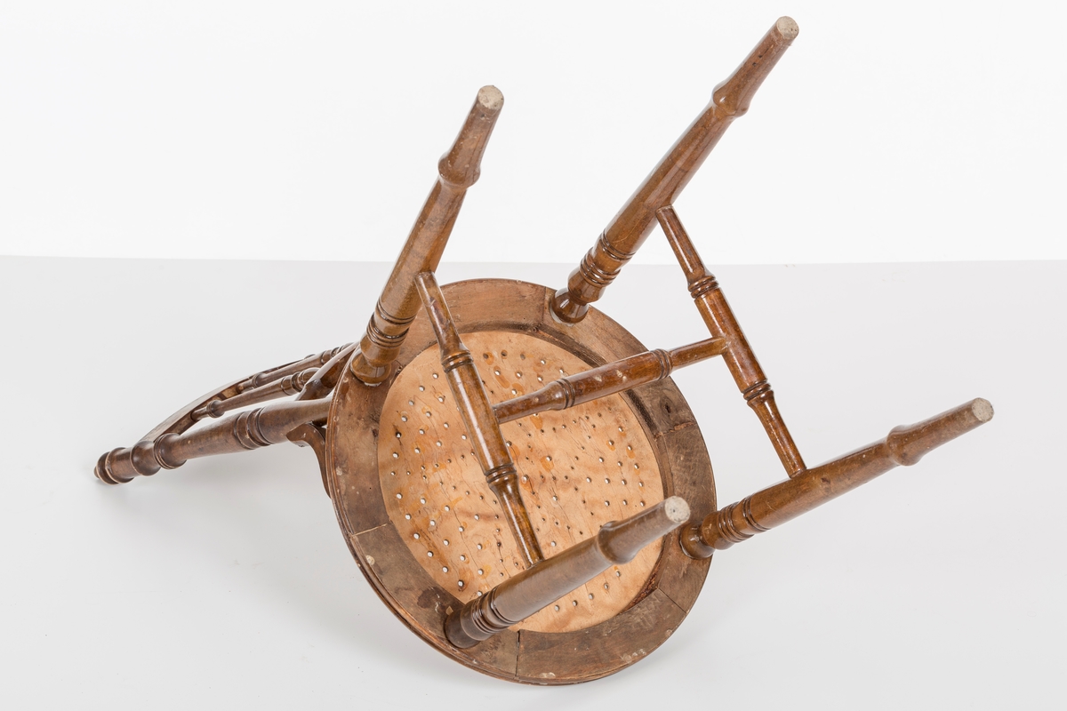 Stol i lakket treverk. Rundt stolsete med hullemønster. Rygg som er svakt buet med spiler og mønster. Dreide ben og spiler i rygg.