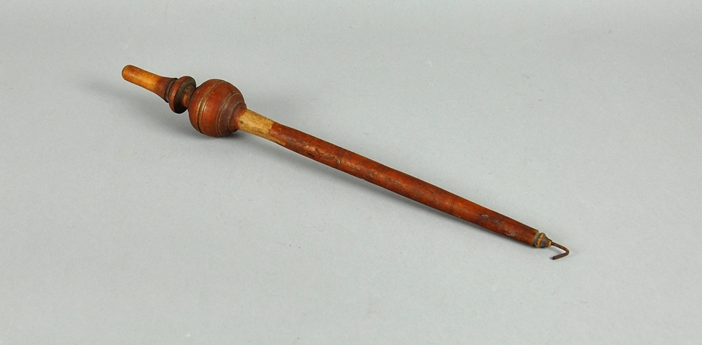 En trestav med kule og snelle i den ene enden og en krok i den andre Håndteinen er malt rødbrun.