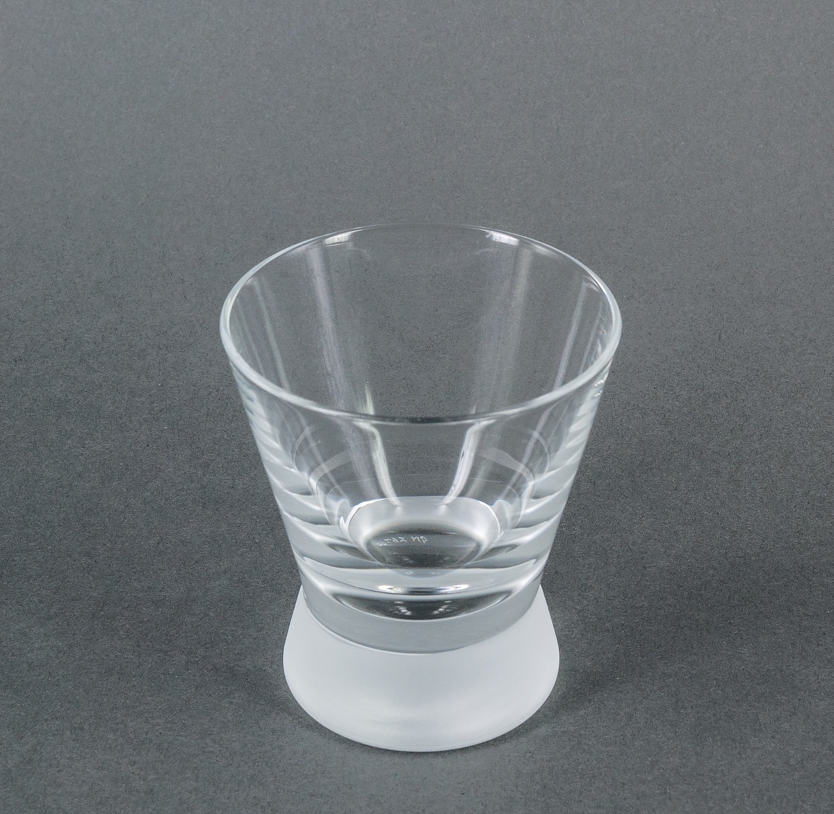 Cocktailglas (tumbler), prov till modell "Queen frostad". Ofärgat med tjock, frostad fot. Raka utåtlutande sidor. Design Gunnar Cyrén för Orrefors Glasbruk.