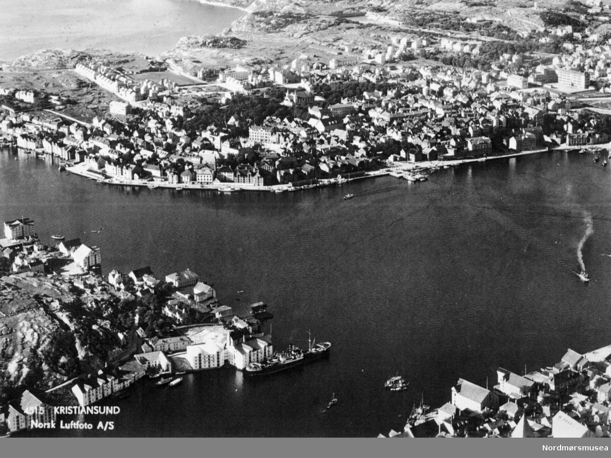 "4515 Kristiansund Norsk Luftfoto A/S". Foto fra Kristiansund og havnebassenget, med Kirkelandet i bakgrunnen, Innlandet på venstre side og Nordlandet på høyre. Fra Nordmøre museums fotosamlinger.