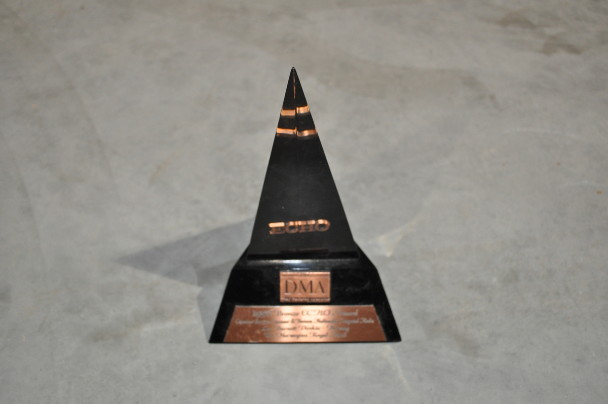 Pyramideformet i svart og blanh hardplast med innskrift:
THE DMA Direct Market Assosiation 1998 Bronze ECHO Award
