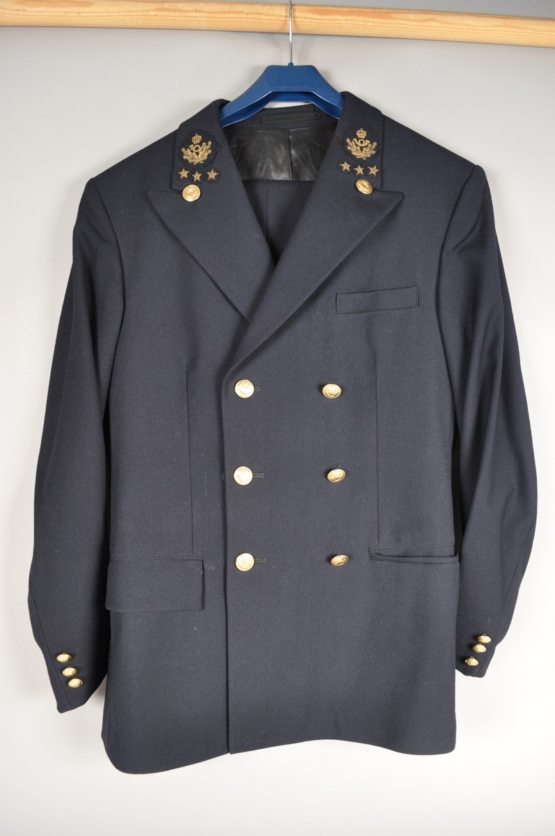 Postuniform bestående av jakke og bukse med posthorn med ekeløv og 3 stjerner. Gullfargede uniformsknapper med posthorn.