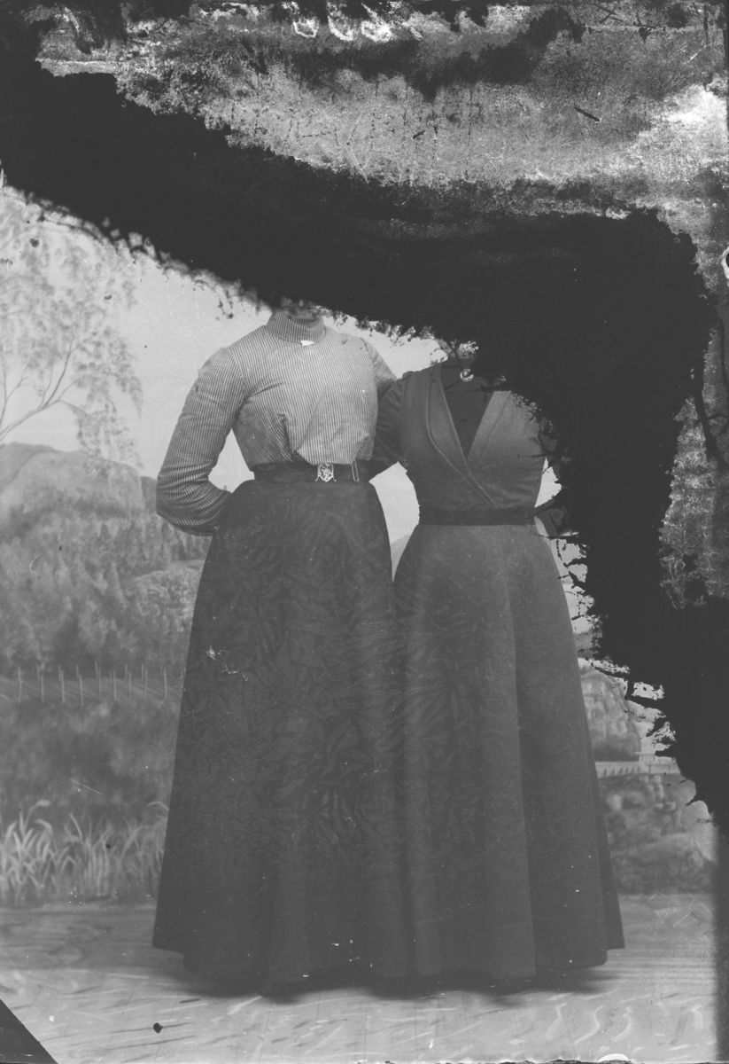 To kvinner som står tett inntil hverandre. Ser ikke hodene da bildet er svart øverst og ned på høyre side. Nevnt Margit H. Rudi.