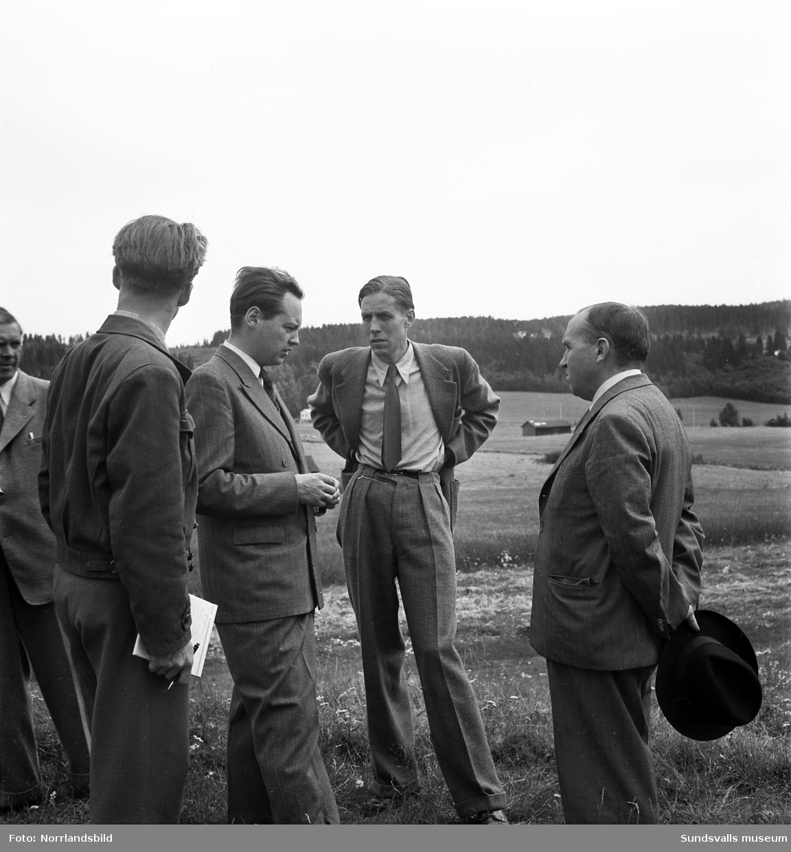 En grupp män står vid gravfältet i Högom. Näst längst till höger på första bilden Sverker Jansson som ledde utgrävningarna tillsammans med Dagmar Selling.