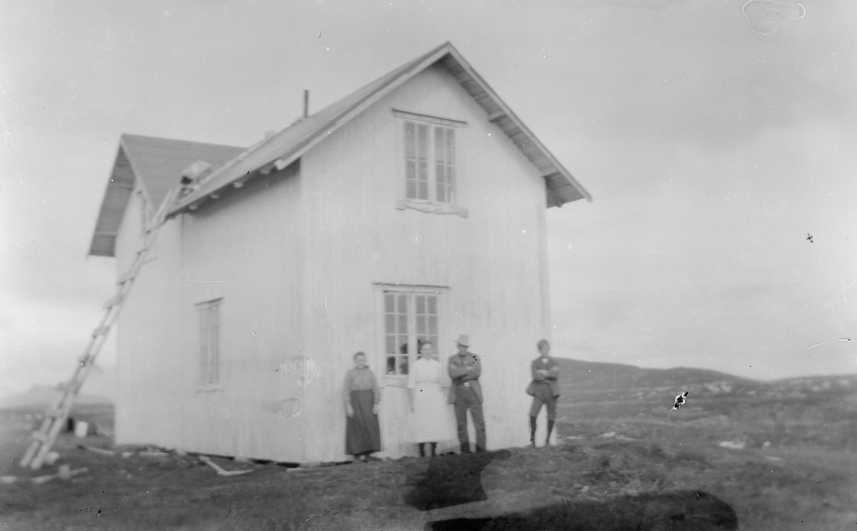 To kvinner og to menn står foran hus.